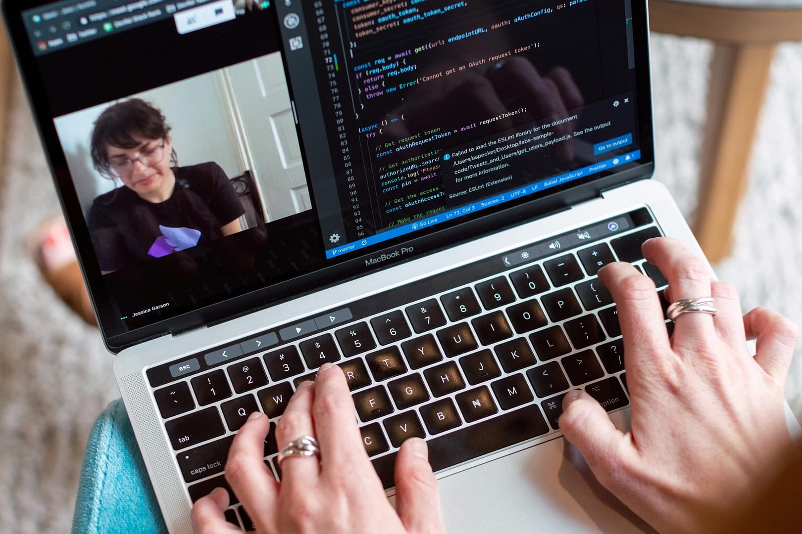 Person coding on a laptop during a video conference, showcasing remote work.